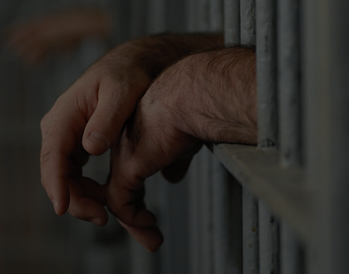 Man with arms out through prison bars
