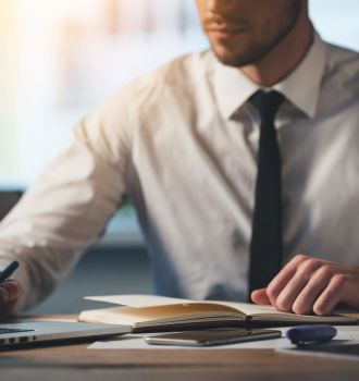 Person in dress shirt and tie writing on document