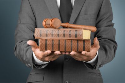 Law books held by a lawyer with a wooden mallet on top of them