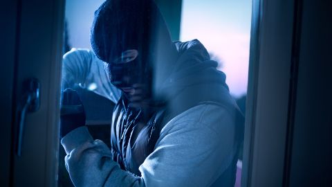 Burglar breaking in and entering a home