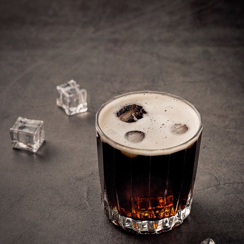 Glass with liquid and ice sitting on a table