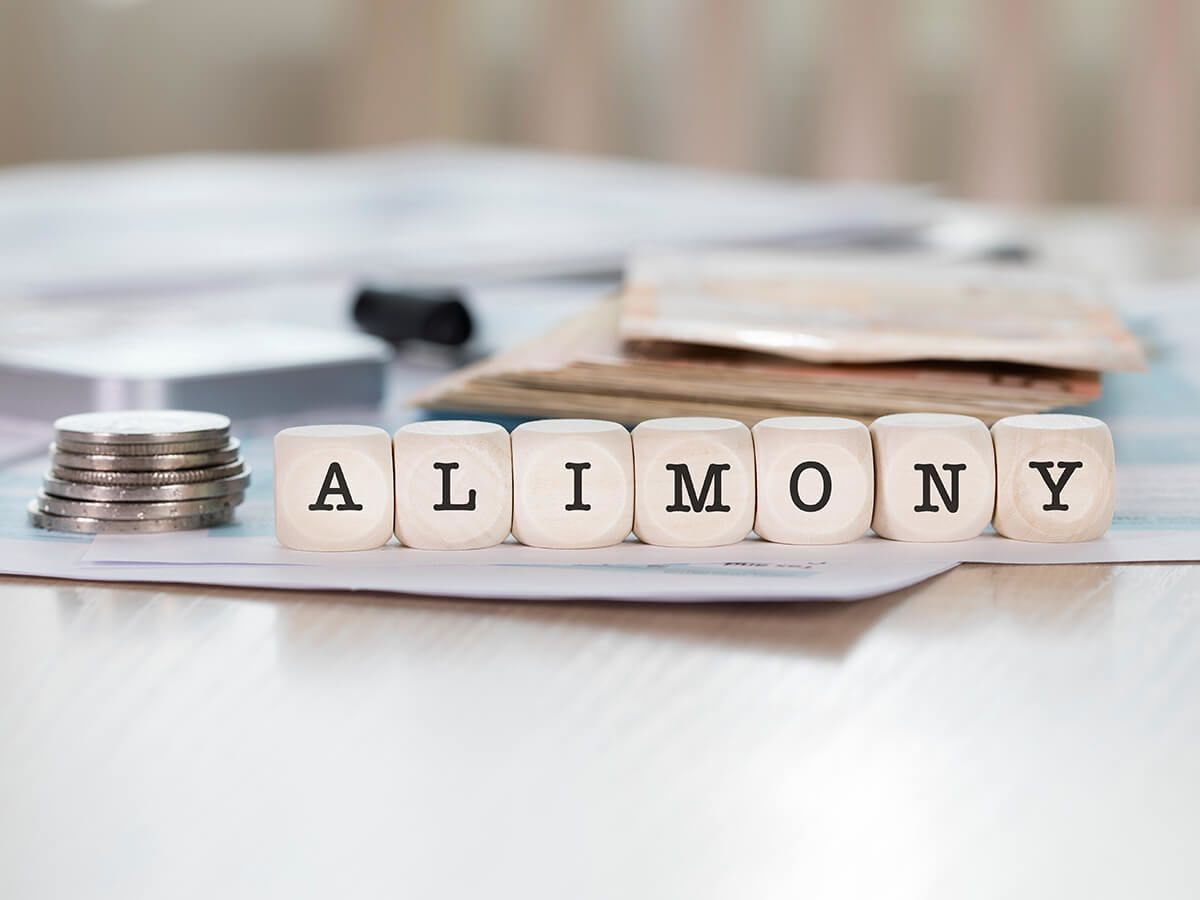 Letter tiles spelling out "Alimony" next to a stack of coins