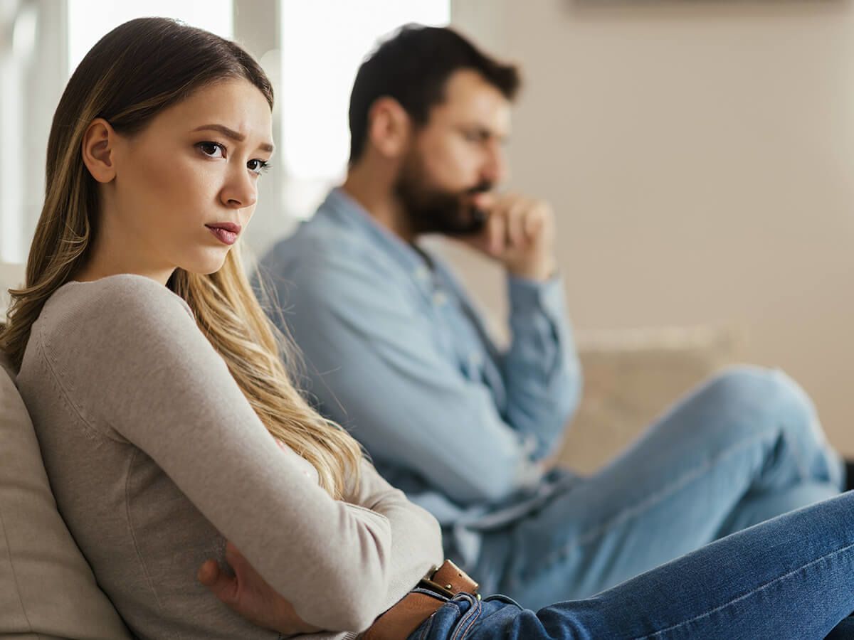 Man and woman look frustrated while sitting together on couch