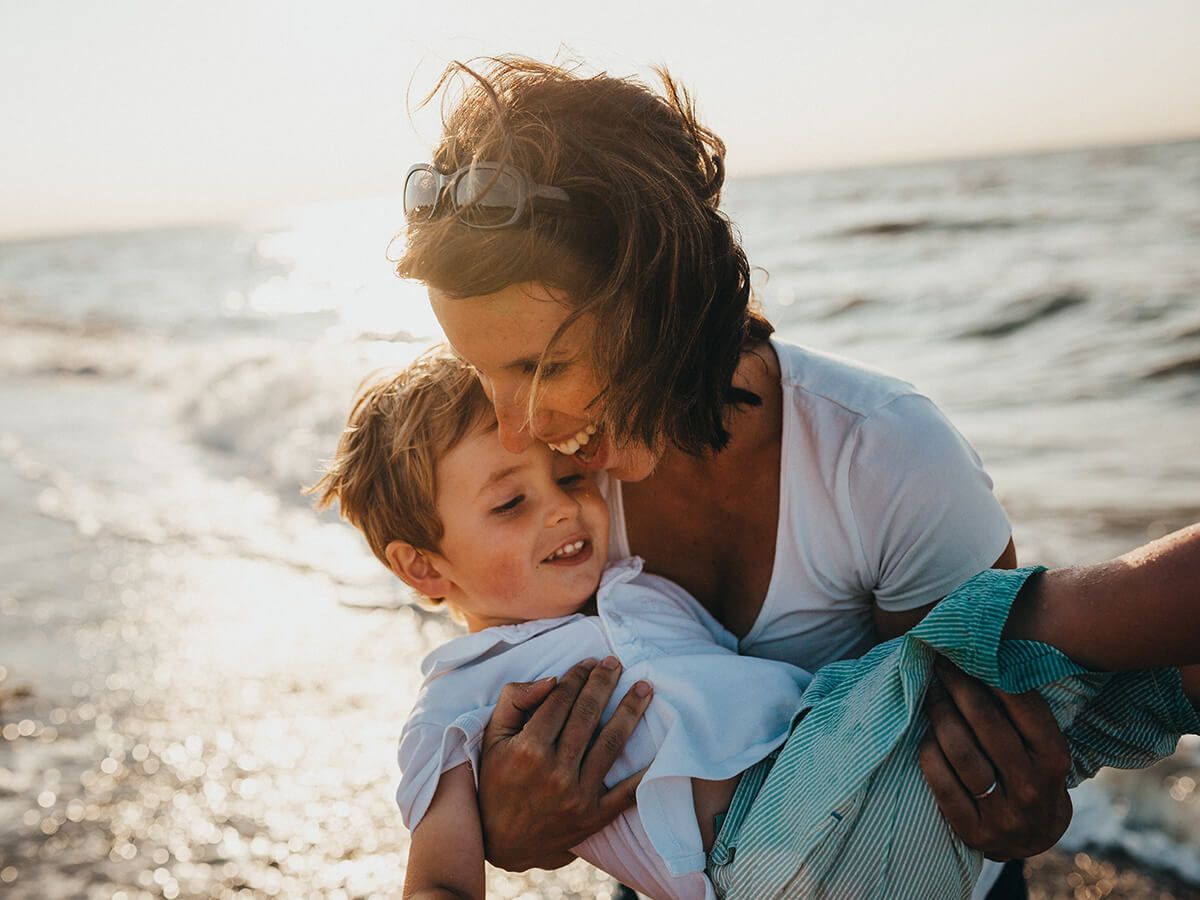 Woman holding a little boy near the ocean