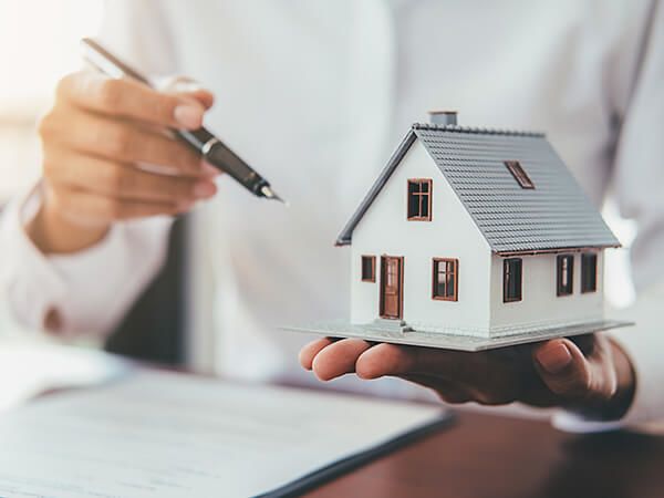 Businessman with pen holding a tiny house