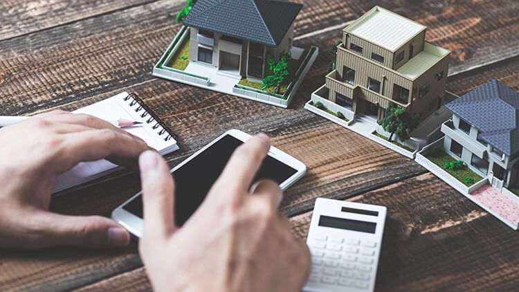 Man with phone and tiny 3-dimensional models of houses