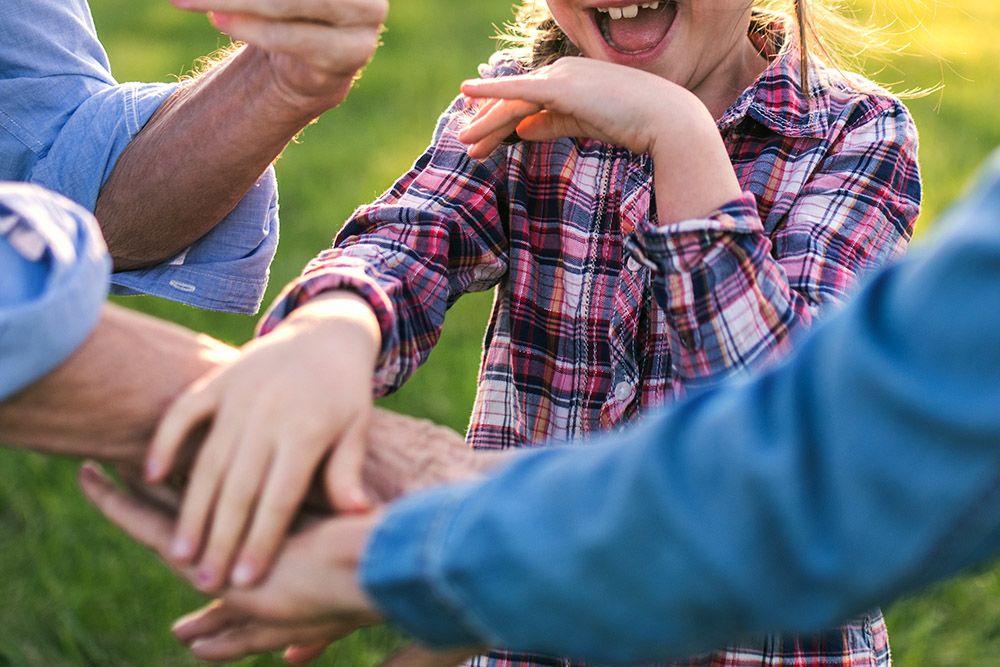 Child playing with adults outside and smiling