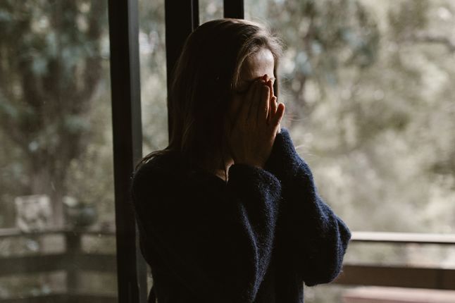 Upset woman with hands folded over face