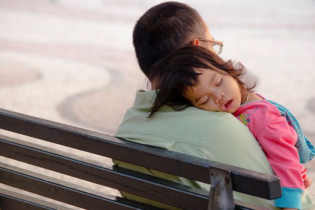 Child sleeping on a man's shoulder