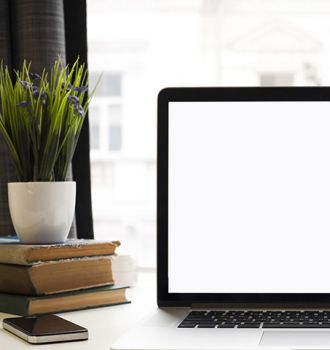 Computer sitting on a desk with books and decor