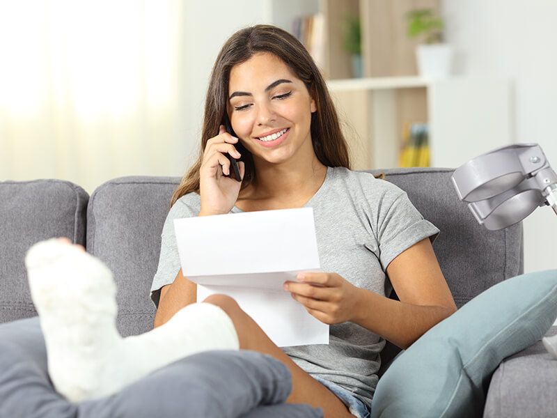 Woman smiling and talking on the phone with her leg in a cast